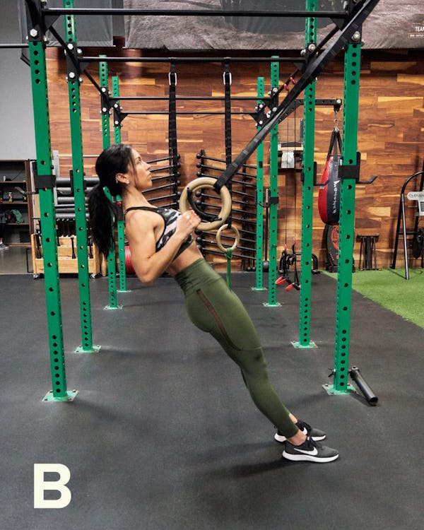 Exercising woman holding gymnast rings. Female taking rest after