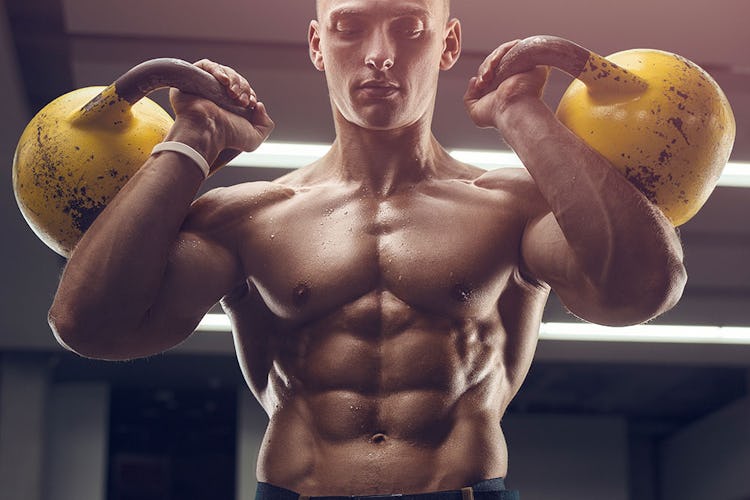 Man with ripped abs holding kettlebells